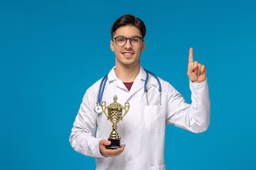 Doctors day cute young brunette guy in lab coat wearing glasses with phonendoscope and trophy